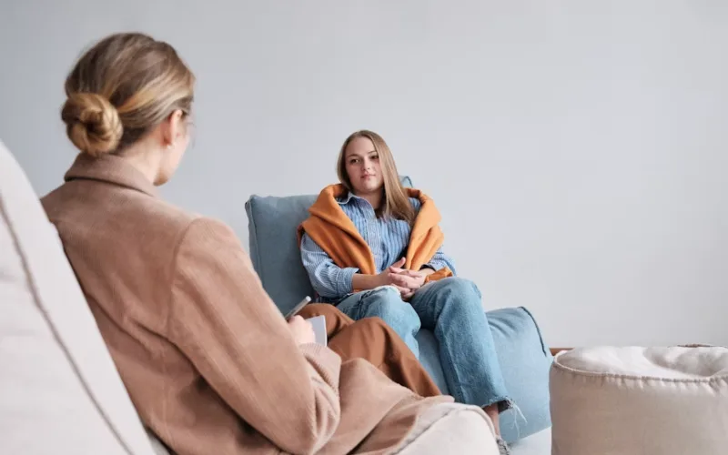 Therapist talking with a young woman during a counseling session in a calm and comfortable office.